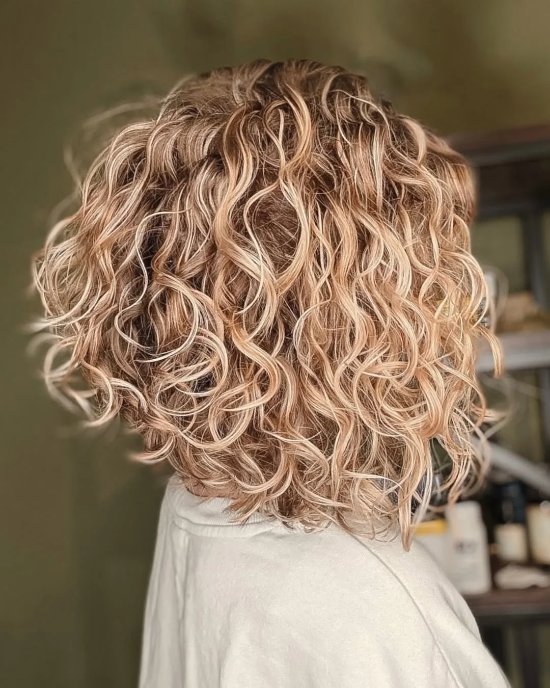 angled summer haircut for round face 2026 + Sunlit Curly Bob With Soft Angled Shape