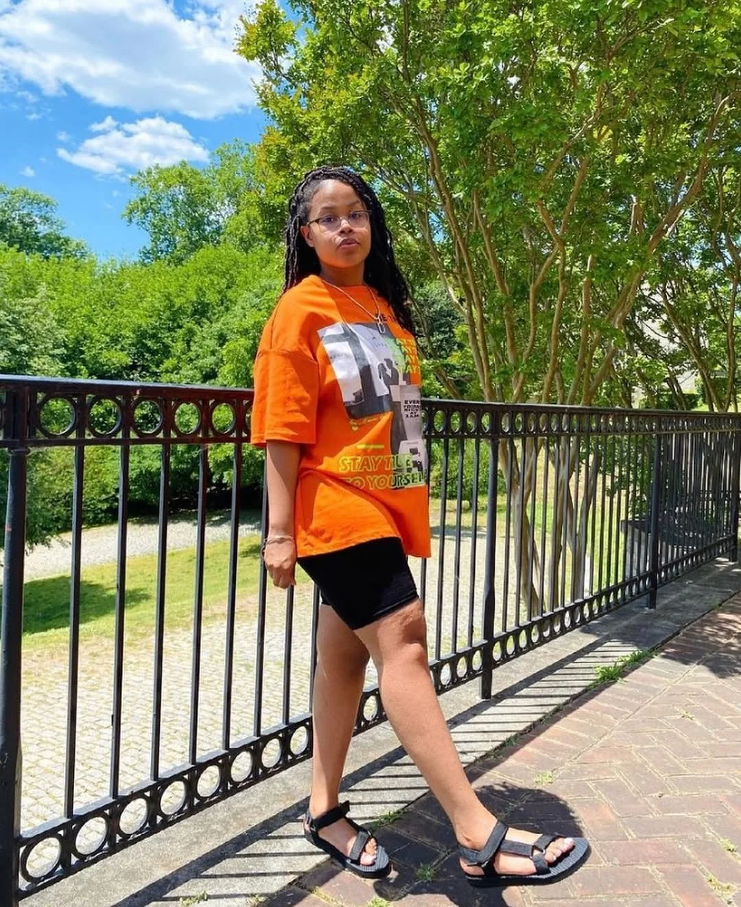 biker shorts outfits summer 2026 Orange Graphic Tee With Black Biker Shorts And Sport Sandals