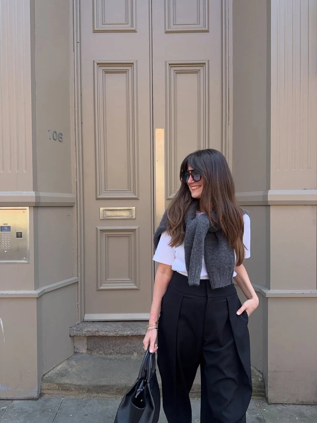fall smart casual work outfit for women 2026 White Tee With Black Pleated Trousers And A Sweater Drape