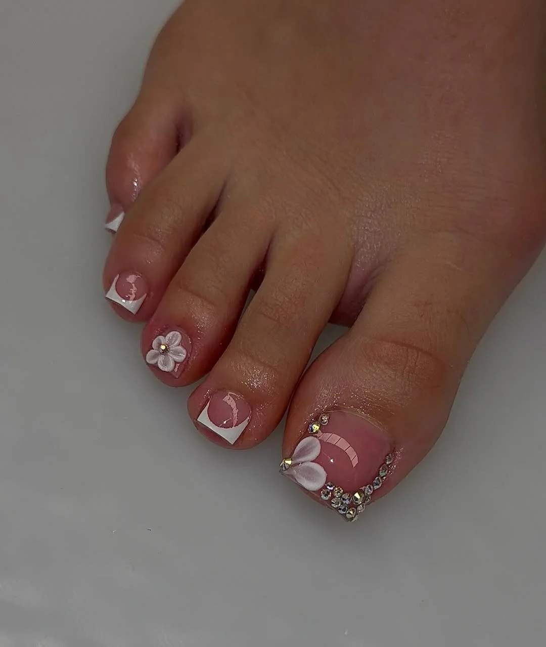 July toe nail colours ideas 2026 White Floral French Toes With Rhinestone Shine