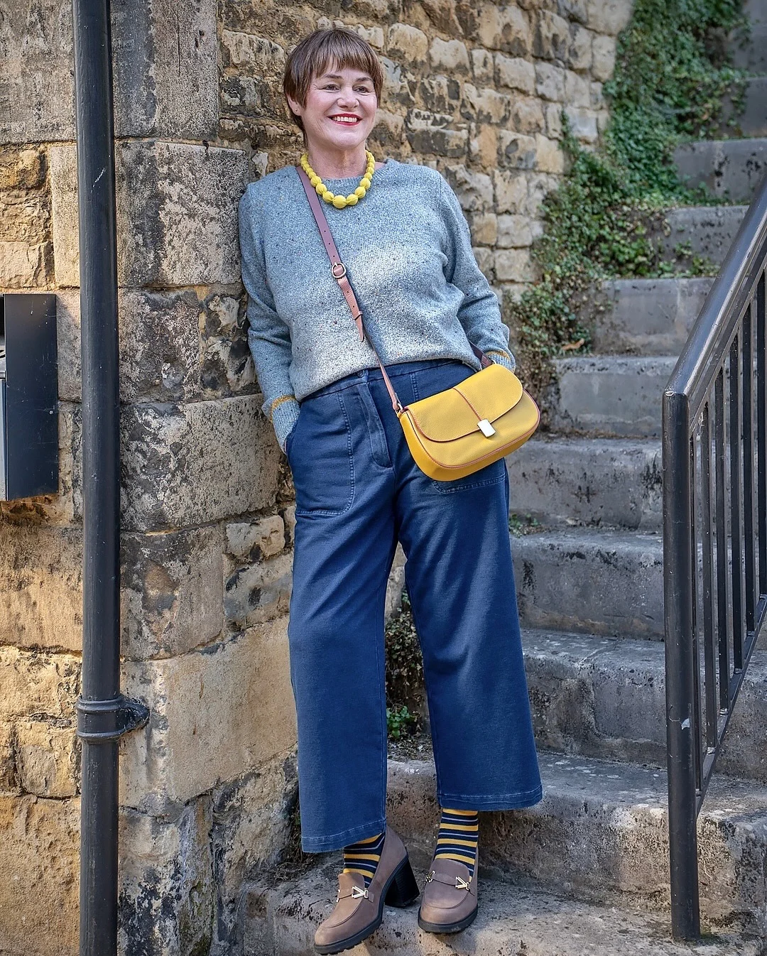 what to wear in fall 2026 over 50 Gray Sweater, Blue Utility Pants, and Yellow Accents