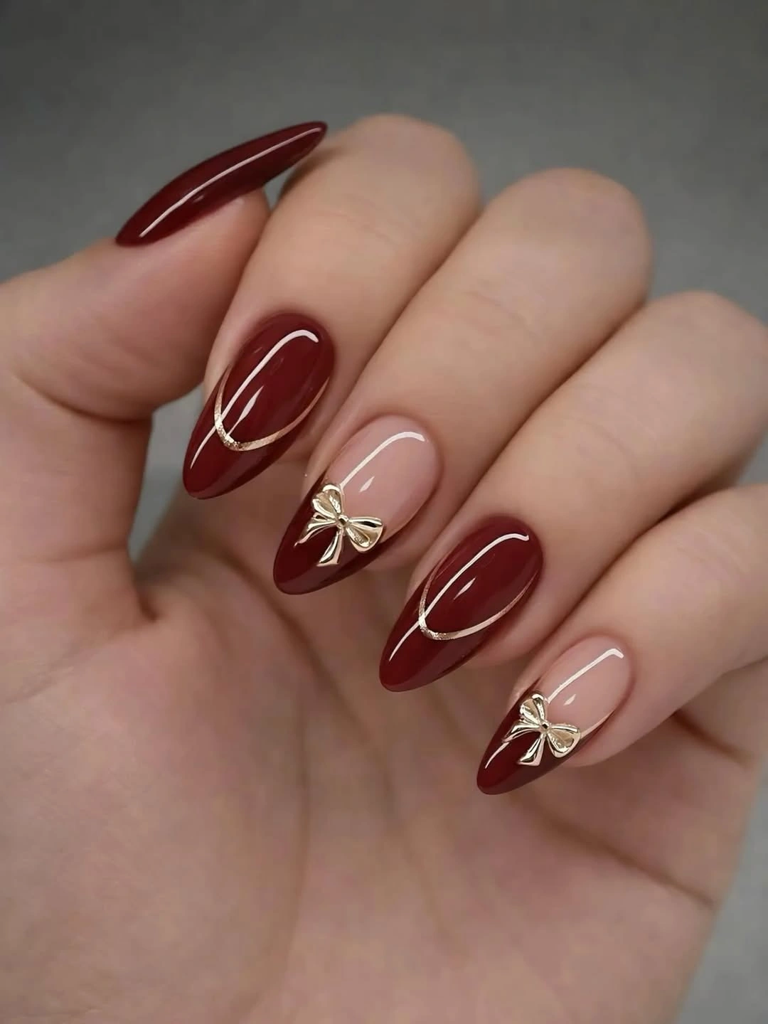 august nails ideas 2026 + Burgundy Almond Nails With Gold Bow Charms