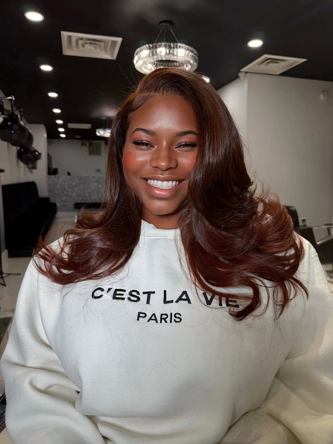 fall hair colors for black women 2026 Glossy Auburn Blowout With Cream Sweatshirt Ease