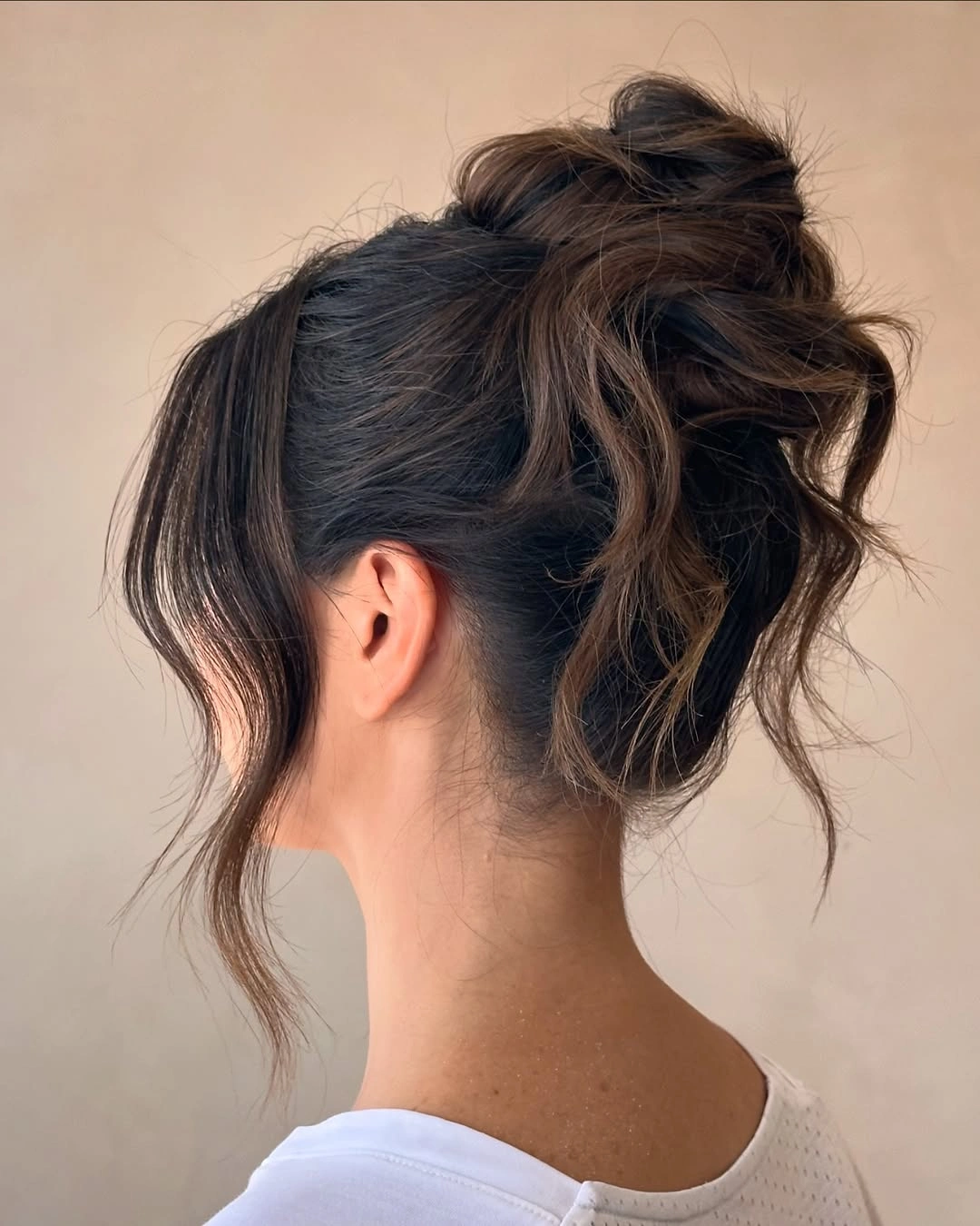 fall hairstyles 2026 Messy Brunette Bun With Soft Face Pieces