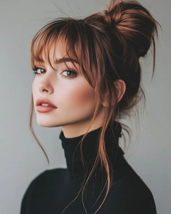 fall hairstyles for long hair 2026 High Messy Bun With Wispy Bangs and Copper Lights