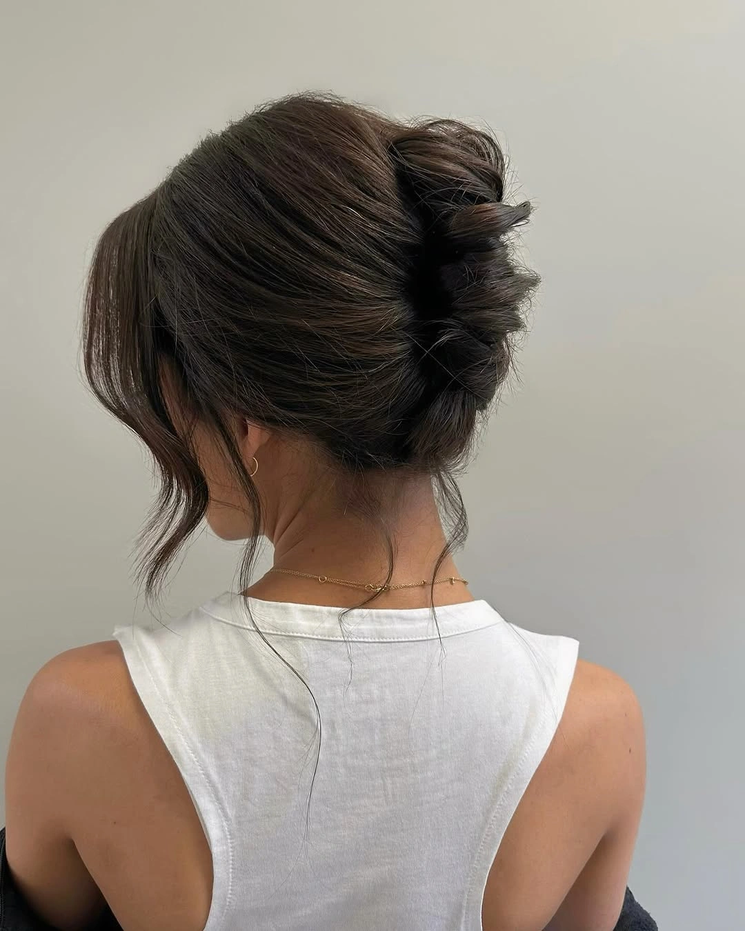 fall hairstyles for wedding guests 2026 Soft Brunette French Twist Bun With Loose Tendrils