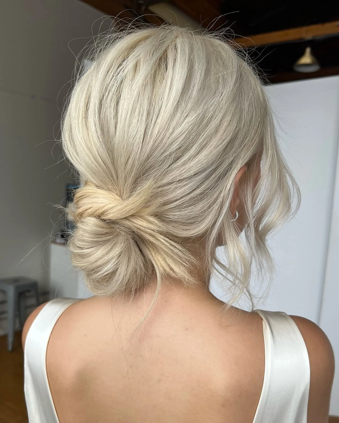 fall hairstyles for wedding guests 2026 Soft Platinum Low Bun For A Minimal Dress