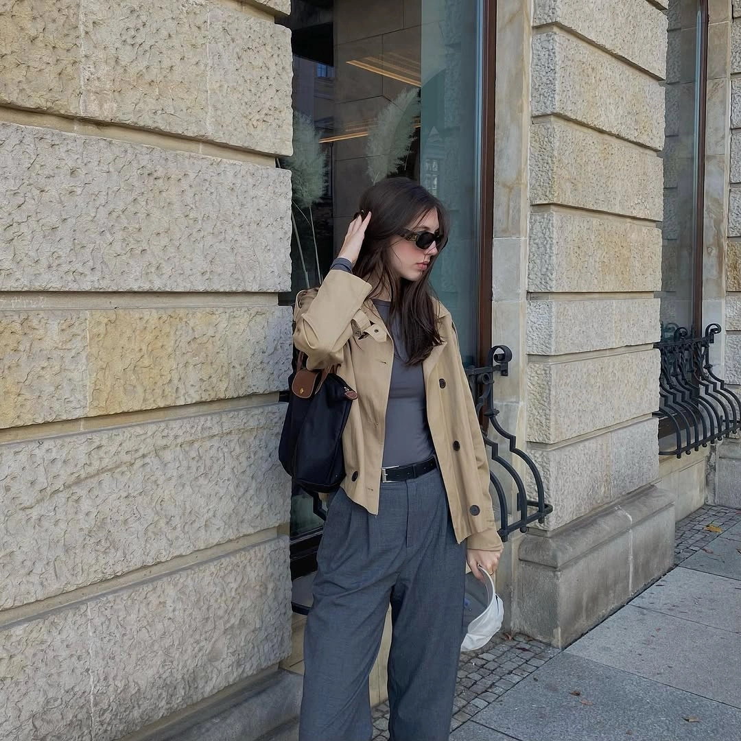 Trench coat fall outfits 2026 + Cropped Tan Trench With Gray Trousers And A Black Backpack