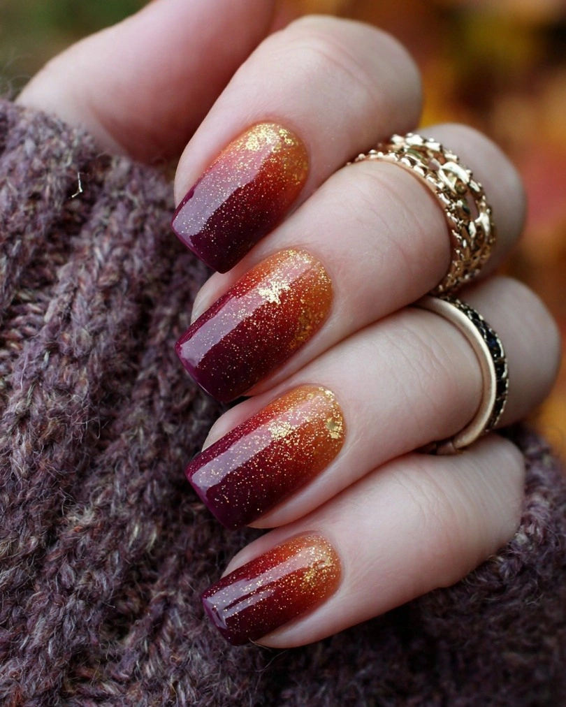 Short berry nails fading into copper glitter at the tips