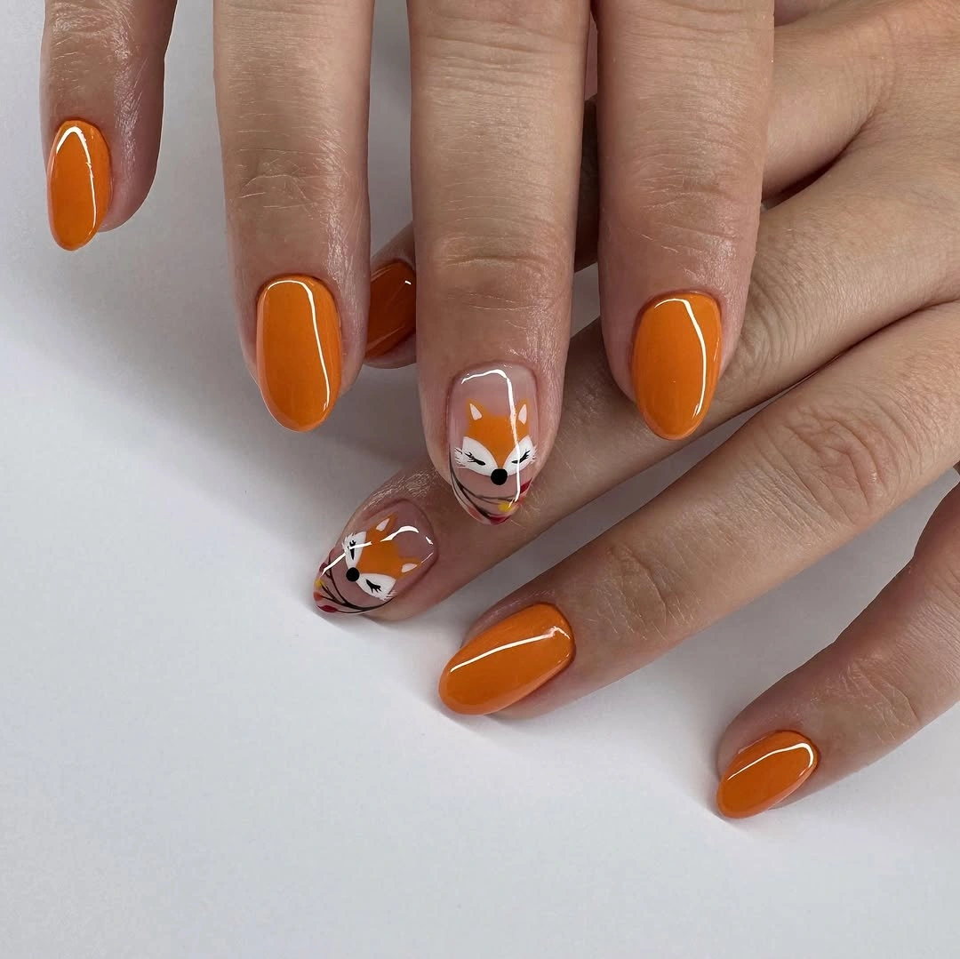 Short orange nails with pale illustrated accent details