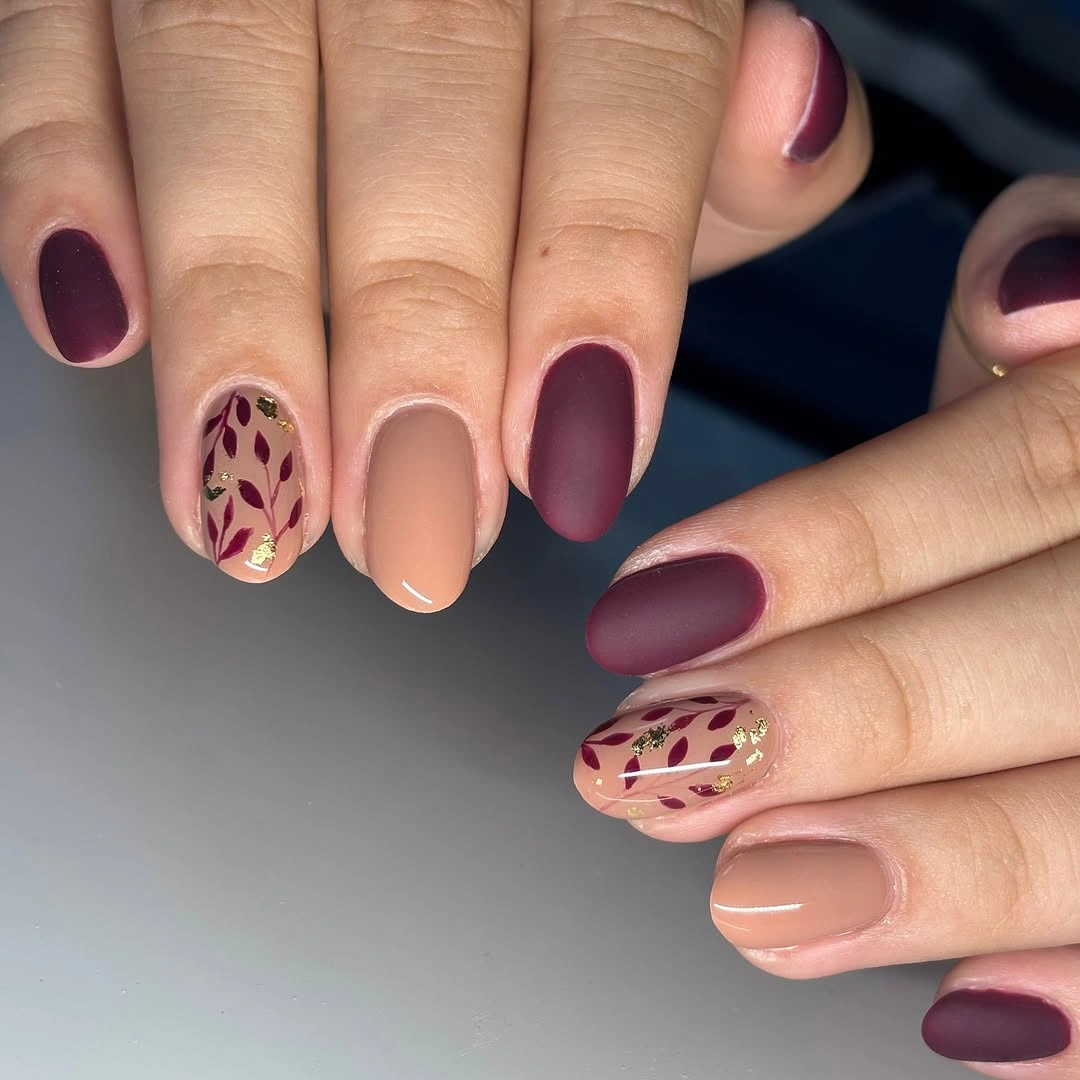 Short burgundy and nude matte nails with botanical accents