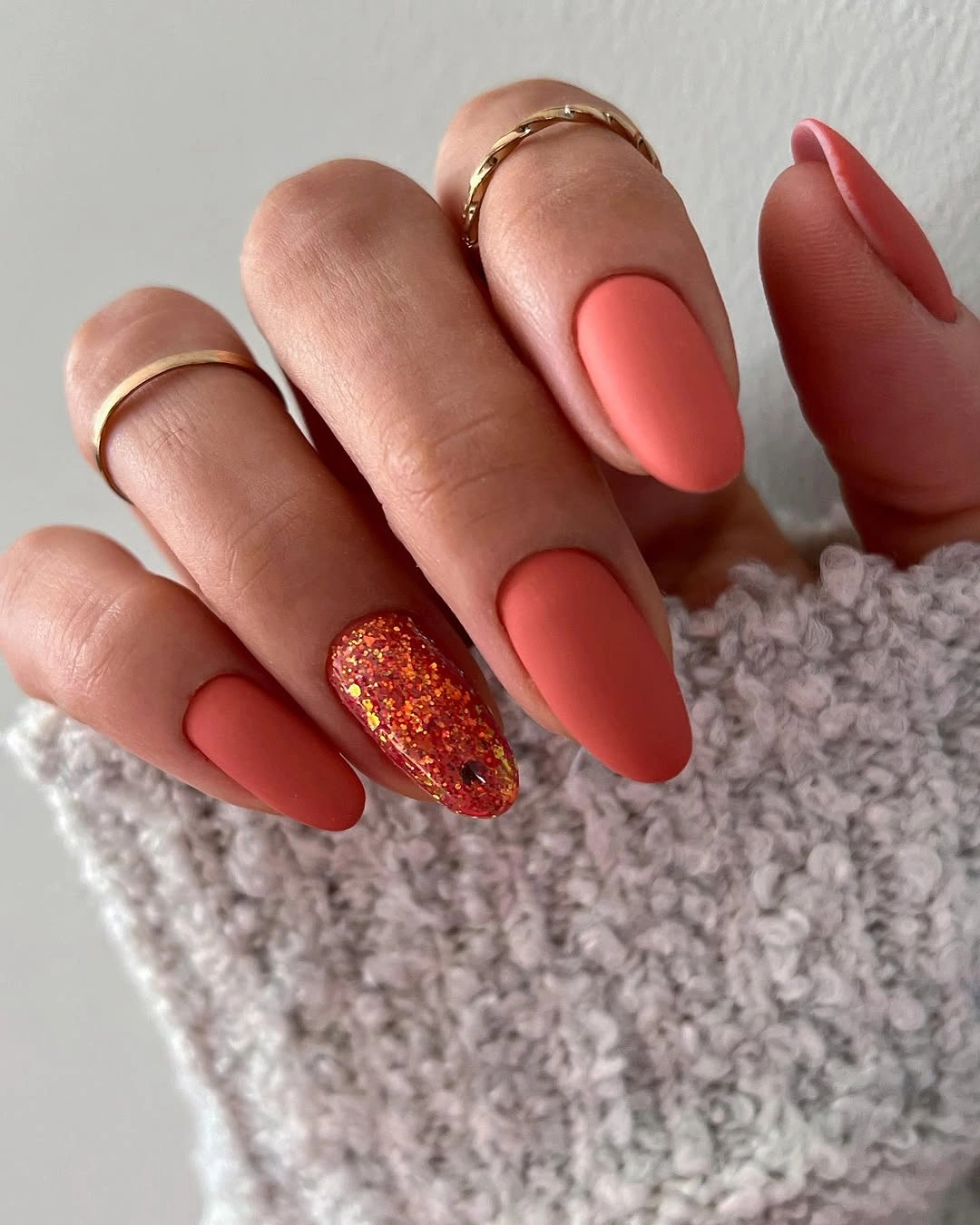 Long coral matte nails with one dense orange glitter accent