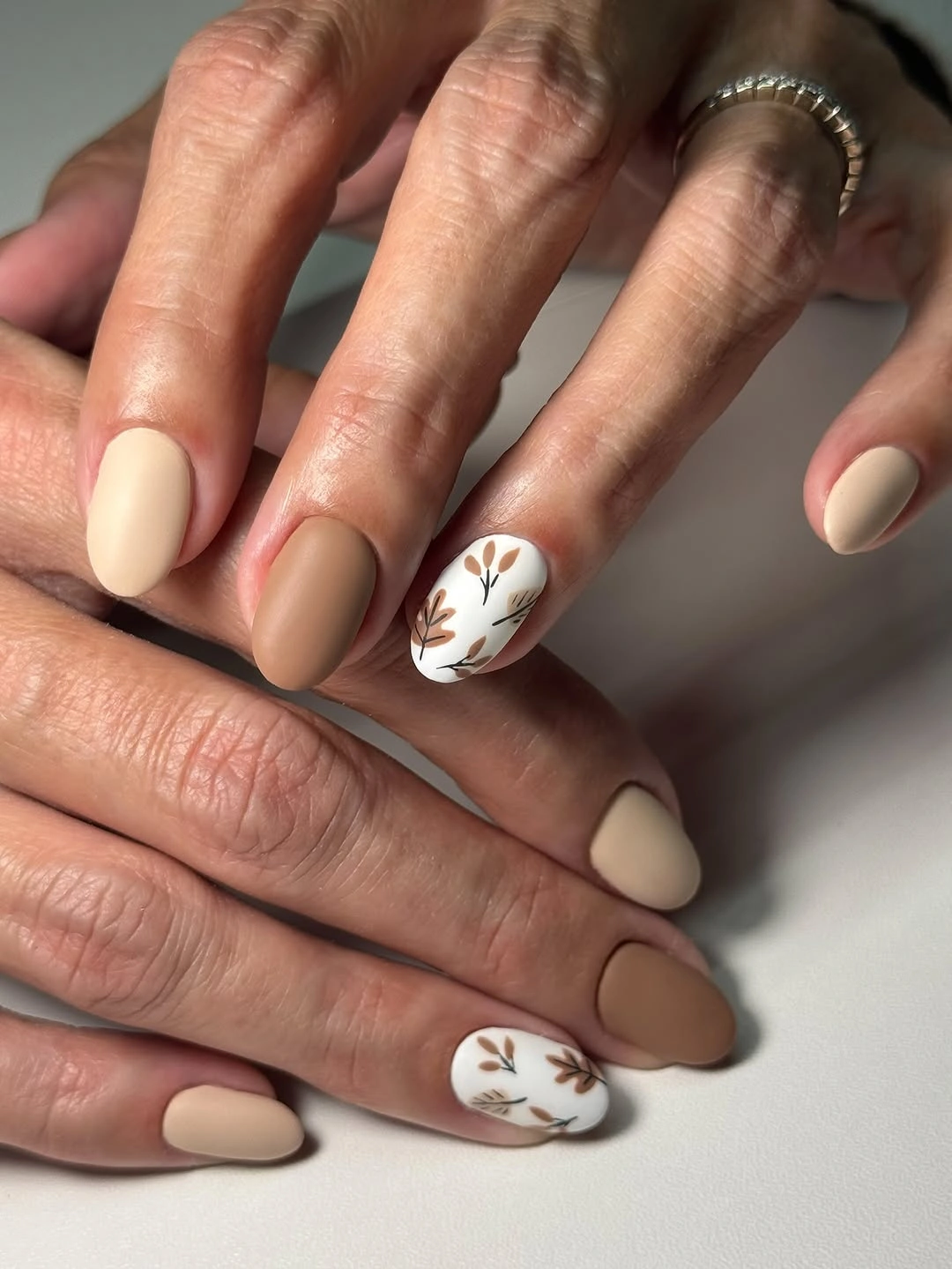 Warm nude matte almond nails with white branch accents