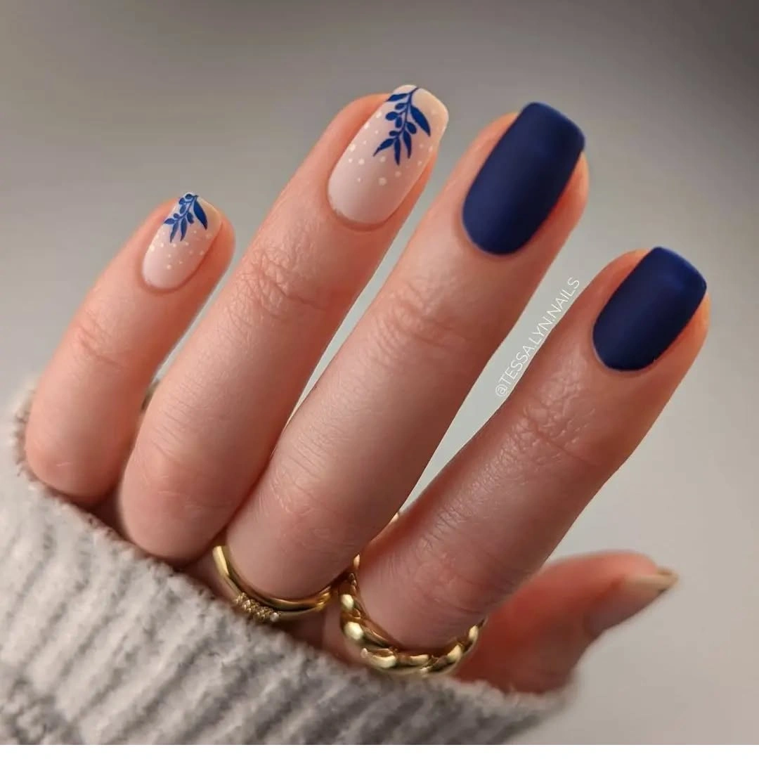 Navy matte almond nails with pale blue botanical accents