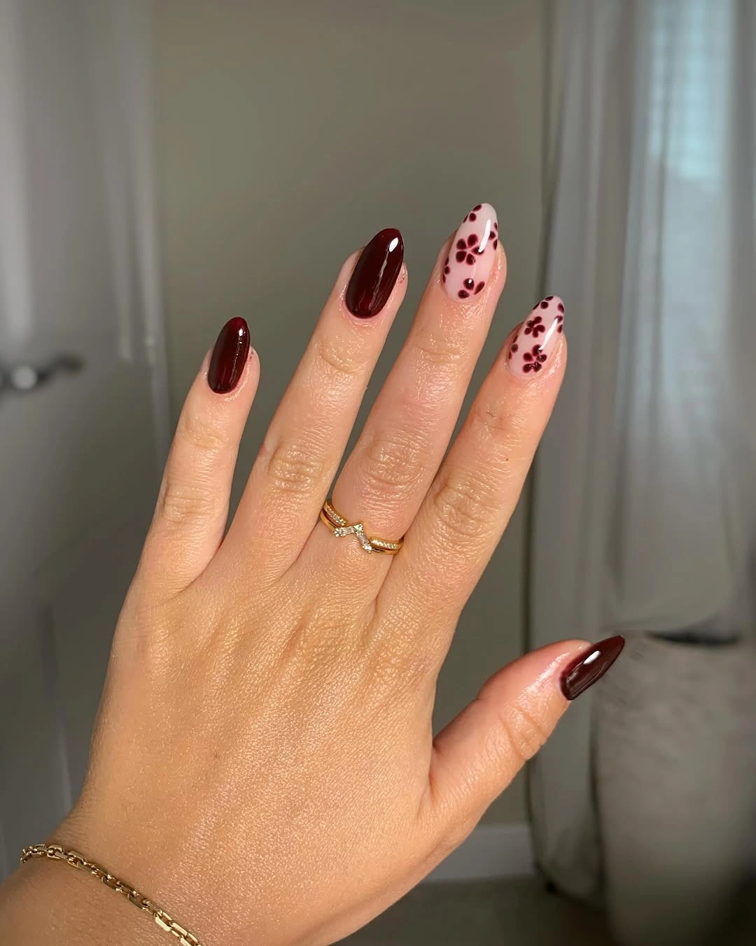 Long nude almond nails with burgundy tips and small dot accents