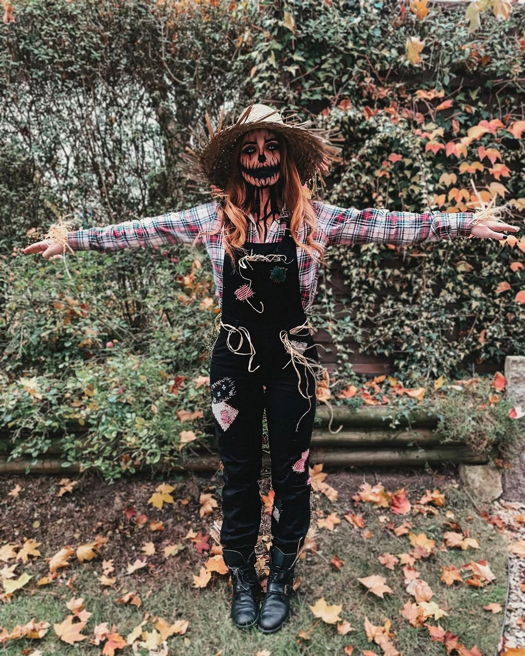 black outfit with straight-legged overalls with a wide-brim hat and open-arm stance