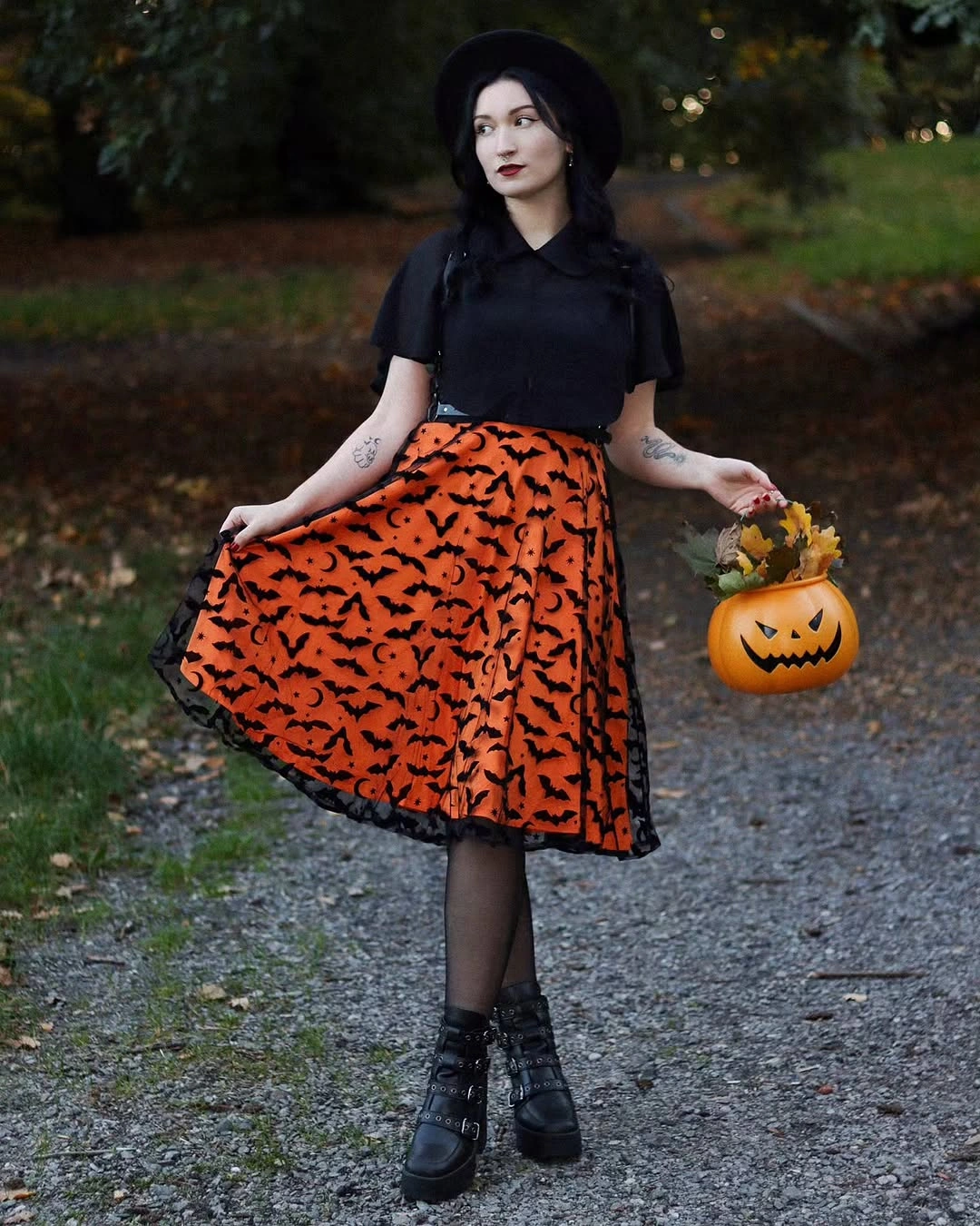 black and vivid orange with small green-brown accessory notes outfit with fitted top, full swing skirt, tights, and sturdy boots