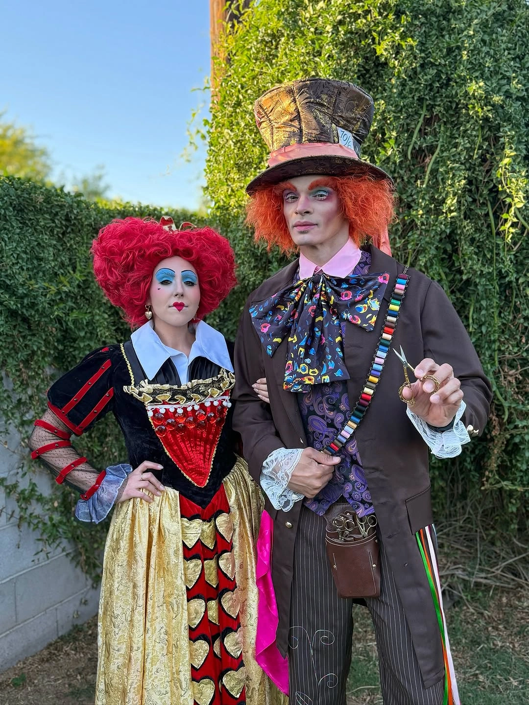 red outfit with ornate short dress beside tall striped suit with top hat