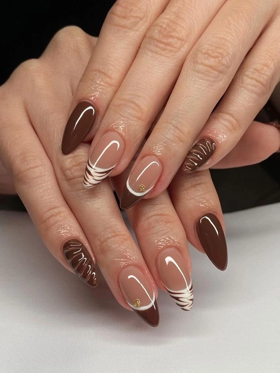 long almond nails with brown tips and cream curved lines