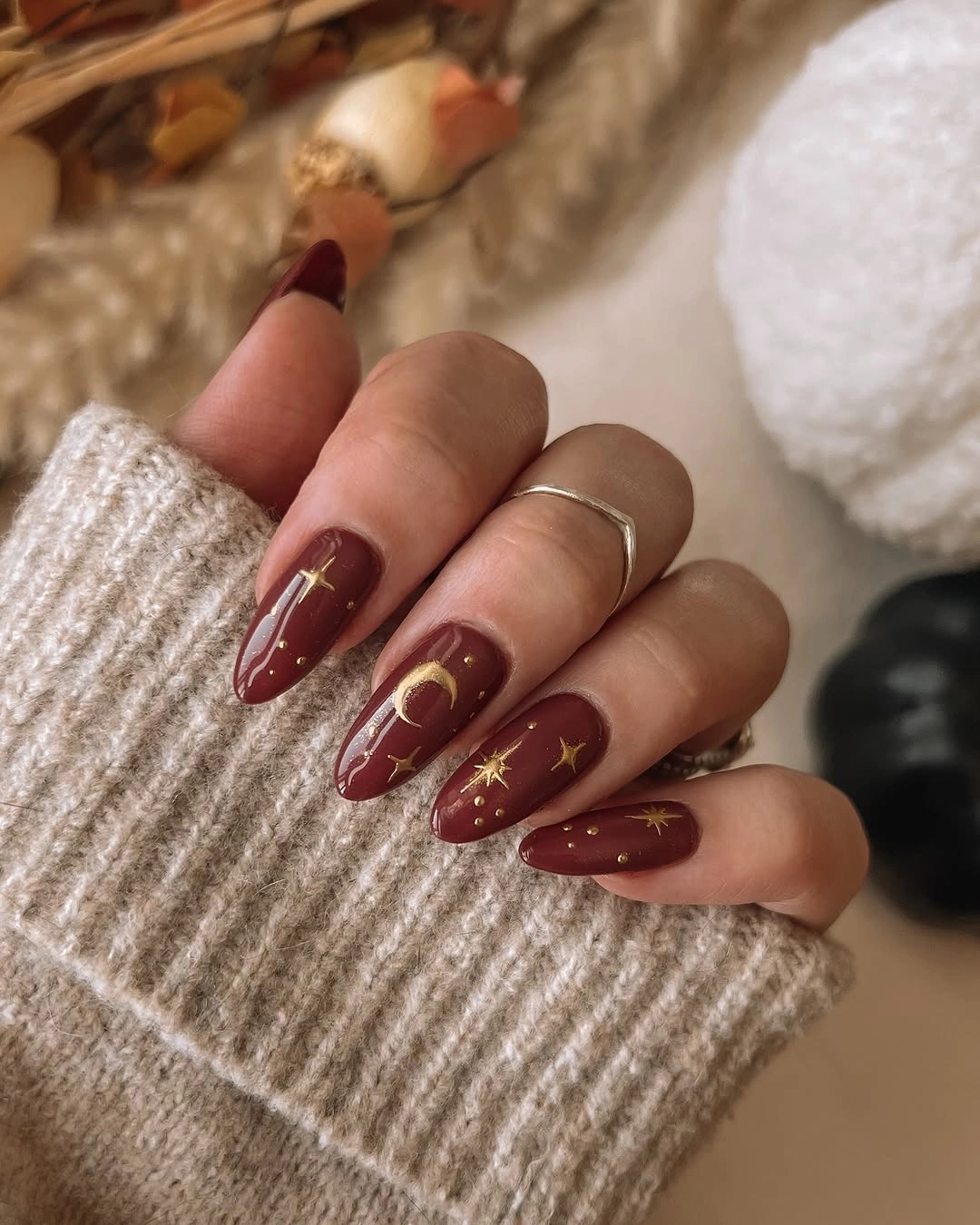 long burgundy almond nails with tiny gold star accents