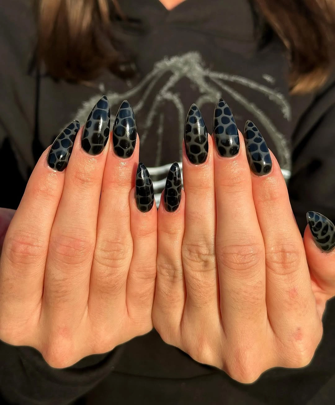long almond nails with a dark repeating patterned texture