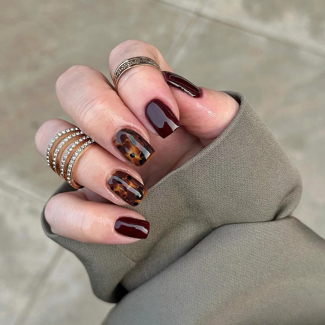 long burgundy almond nails with warm patterned accents