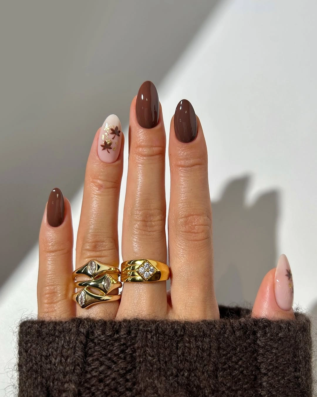Long brown almond nails with one pale floral accent