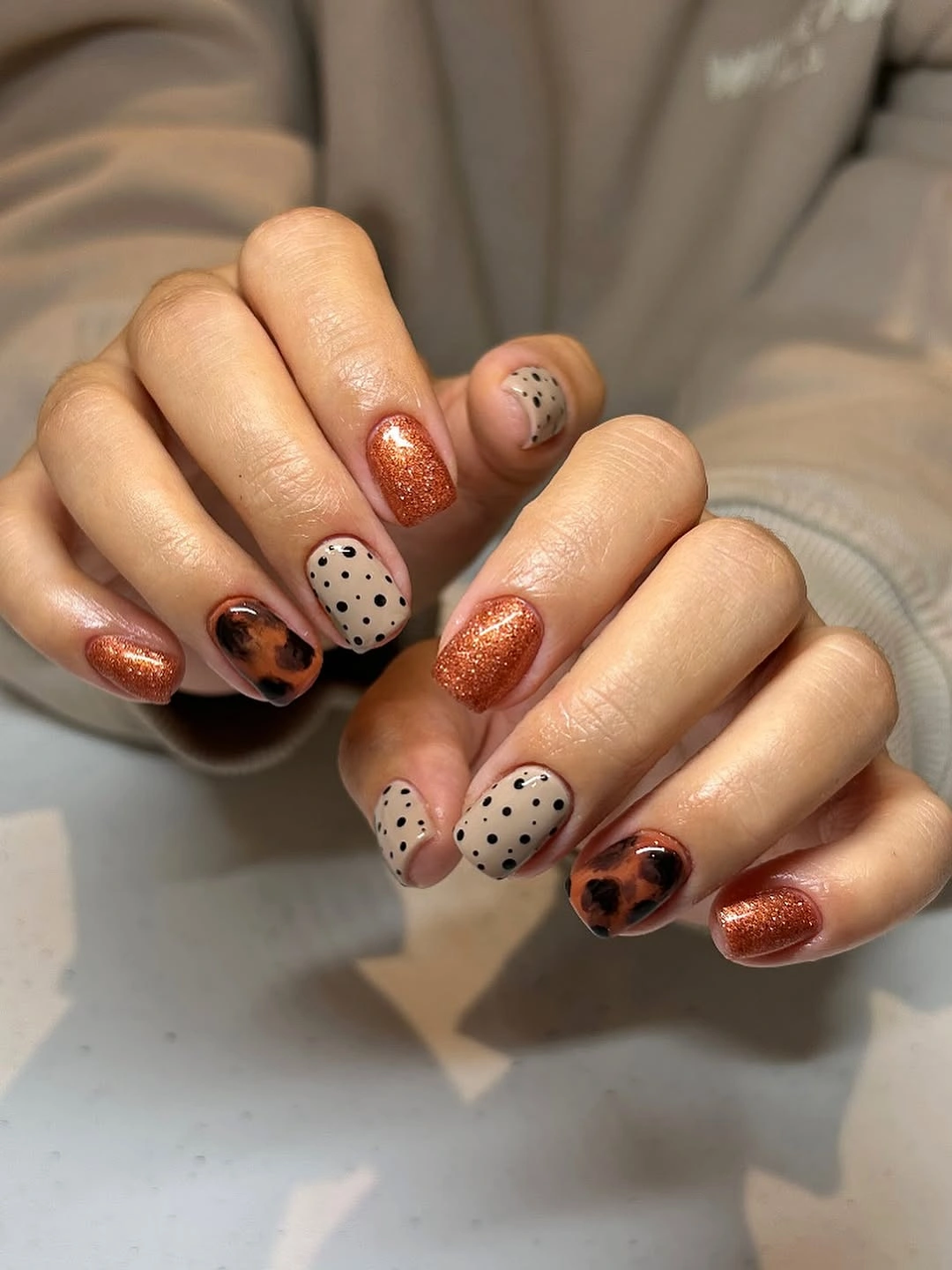 Short copper shimmer nails with dotted neutral accents