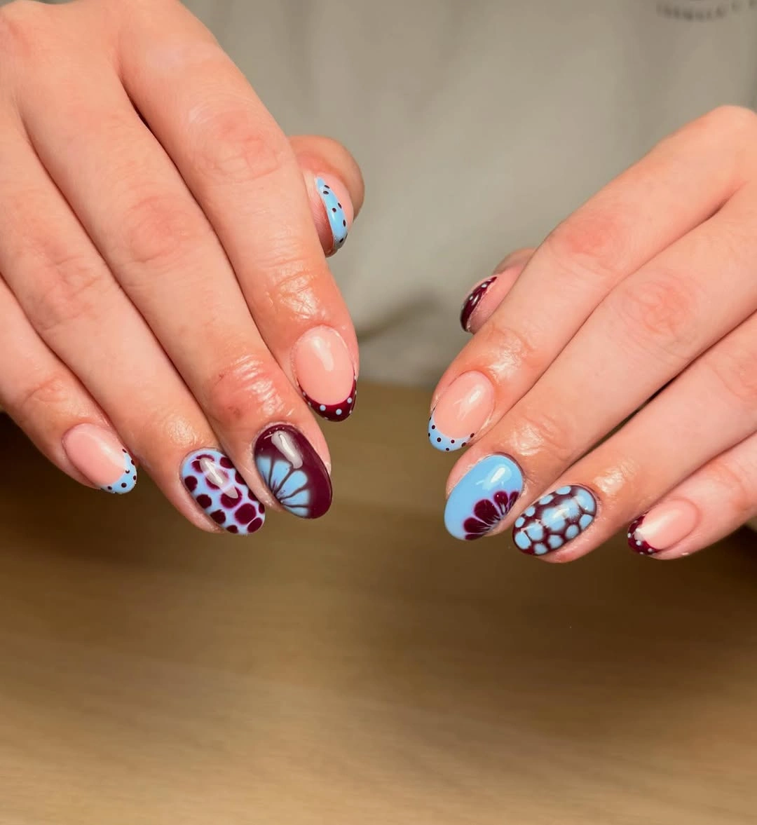 short nude nails with blue tips and wine-red motifs