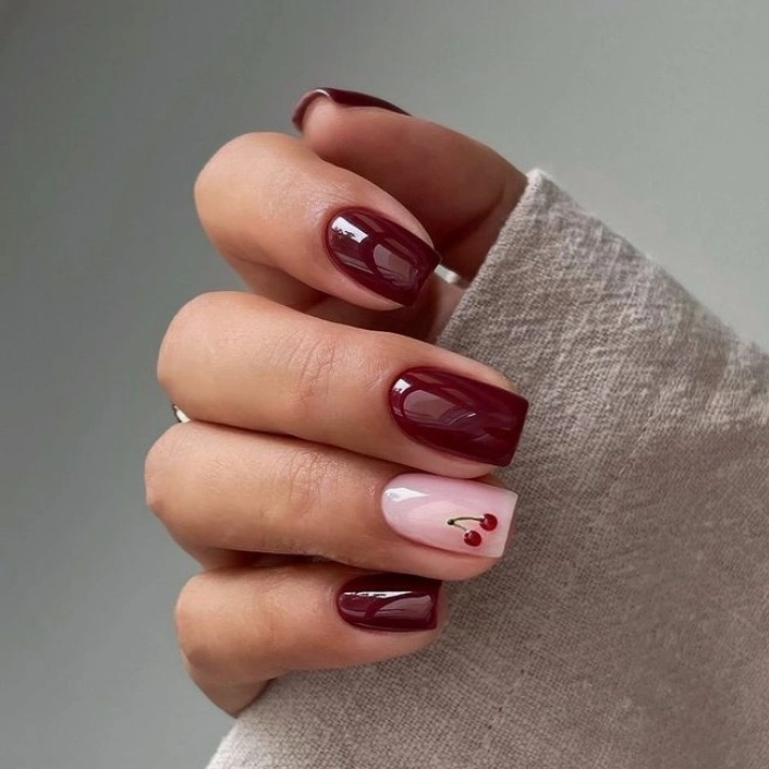 short burgundy nails with one pale accent and tiny red marks