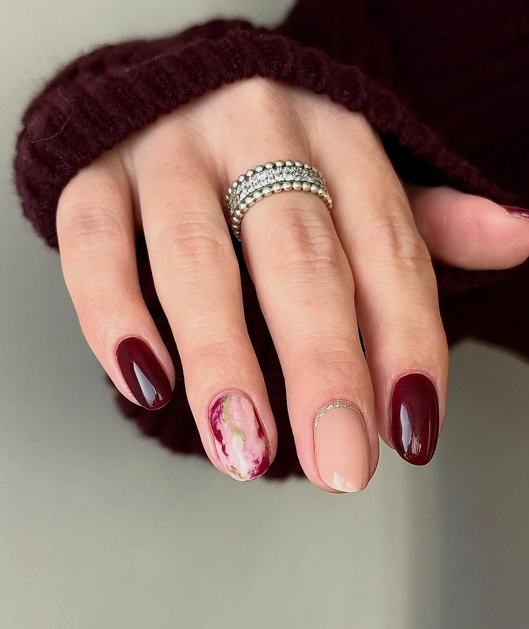 short rounded burgundy nails with small white petal accents