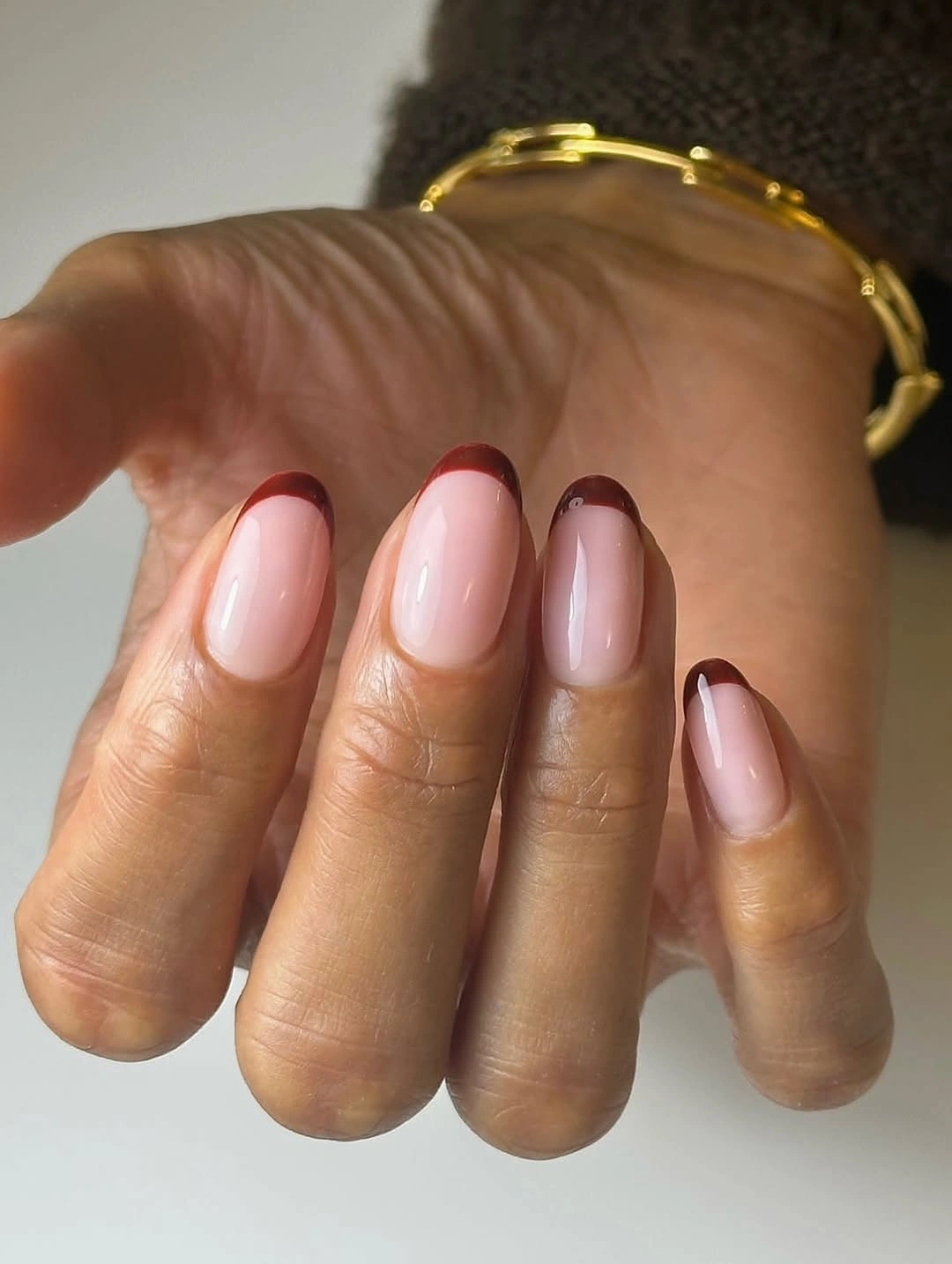 short sheer pink nails with brown French tips