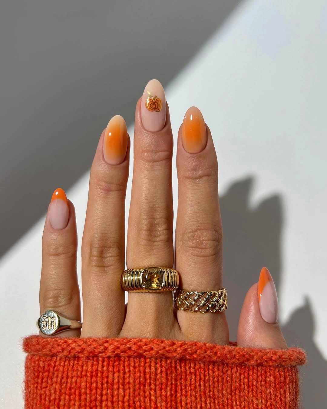 Glossy orange almond tips with a tiny warm metallic detail