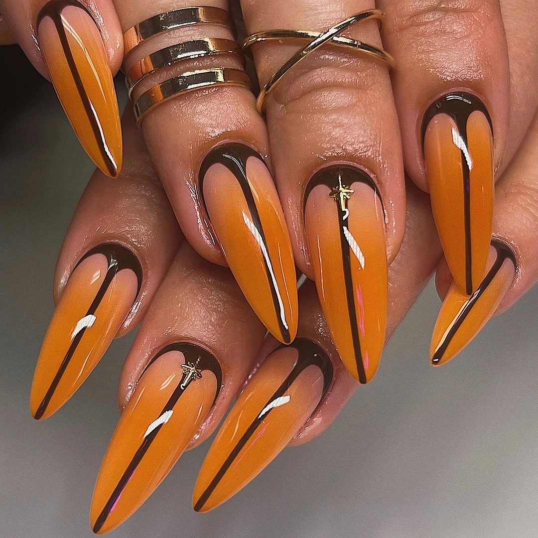 Vivid orange stiletto nails with dark framed line work