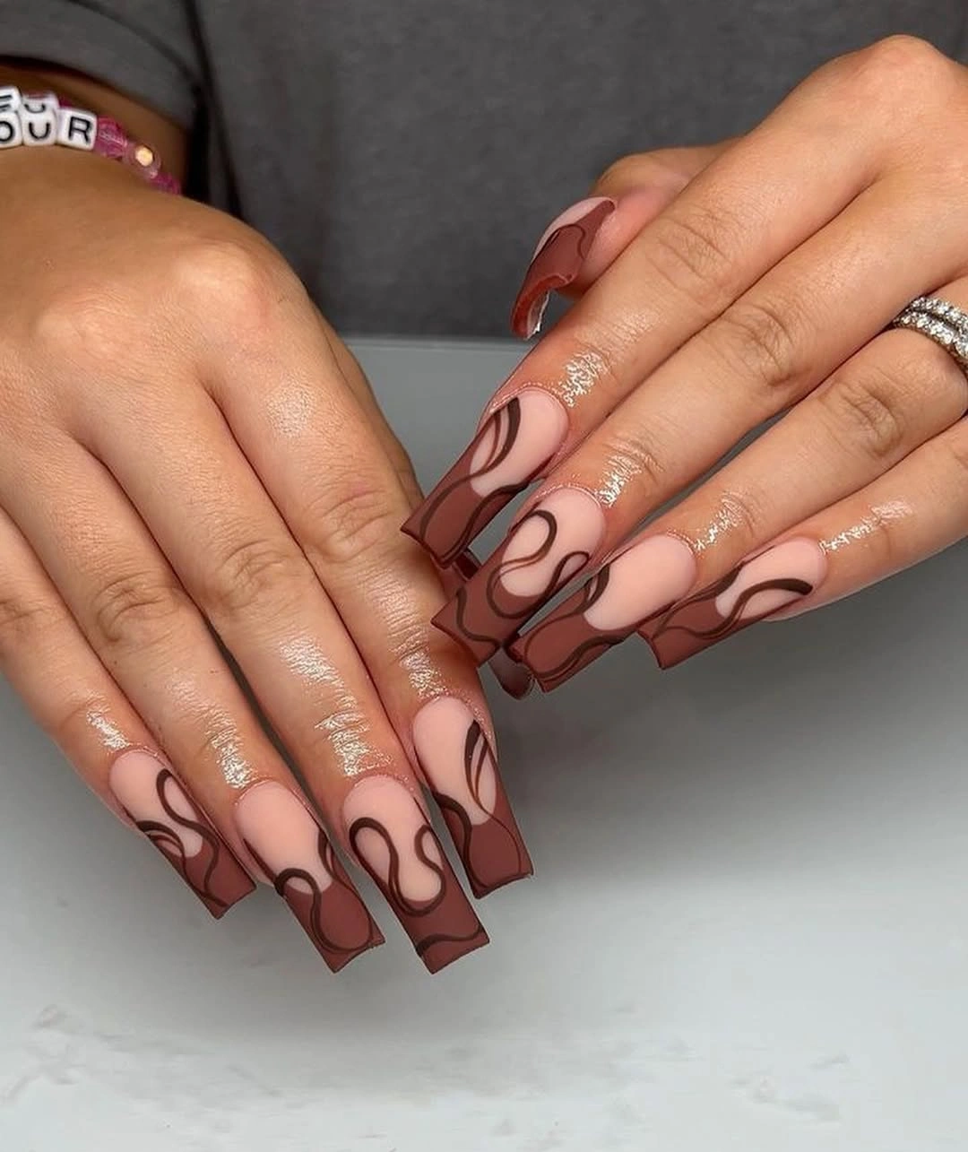 long square nails with brown loops over sheer pink