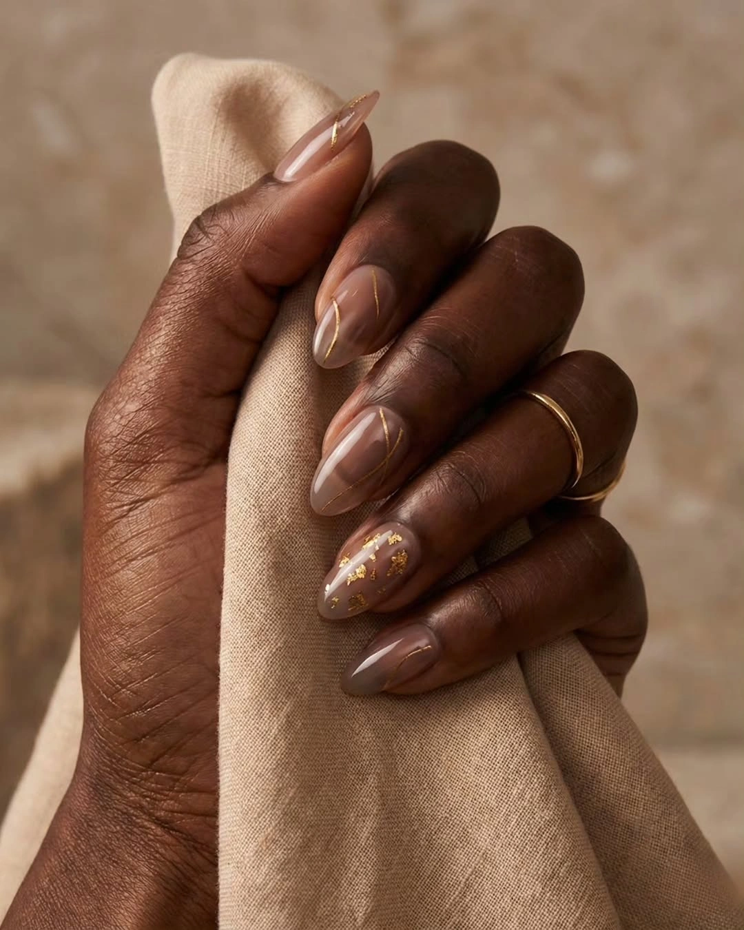 sheer nude almond nails with small gold-looking flecks
