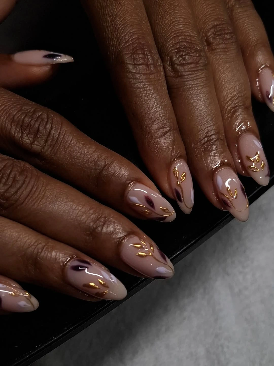 long nude almond nails with fine gold curves