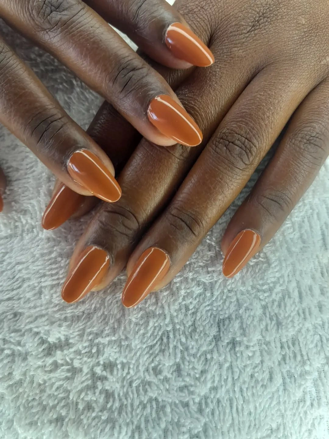 glossy burnt-orange almond nails on dark skin
