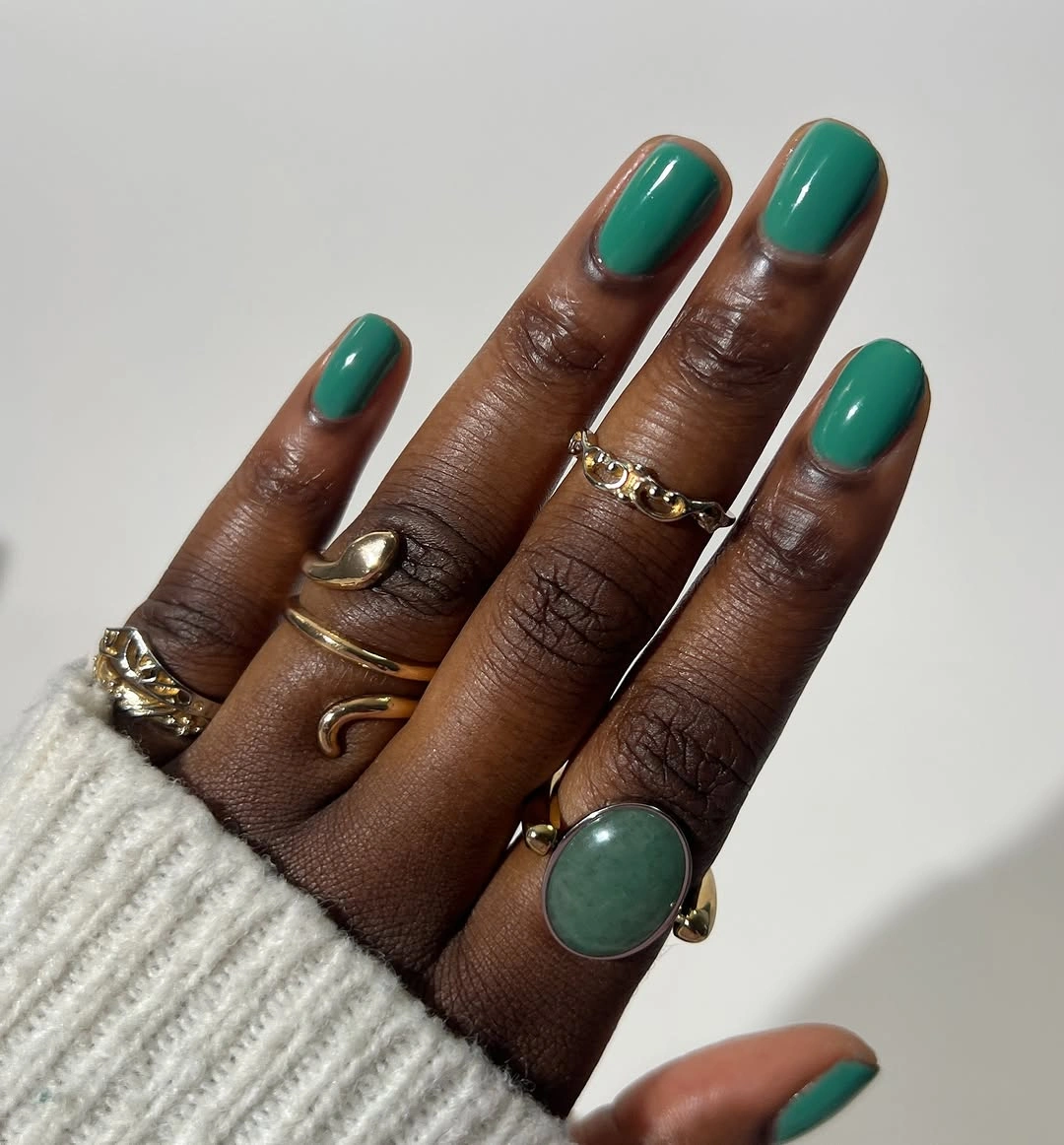 glossy teal-green oval nails on dark skin