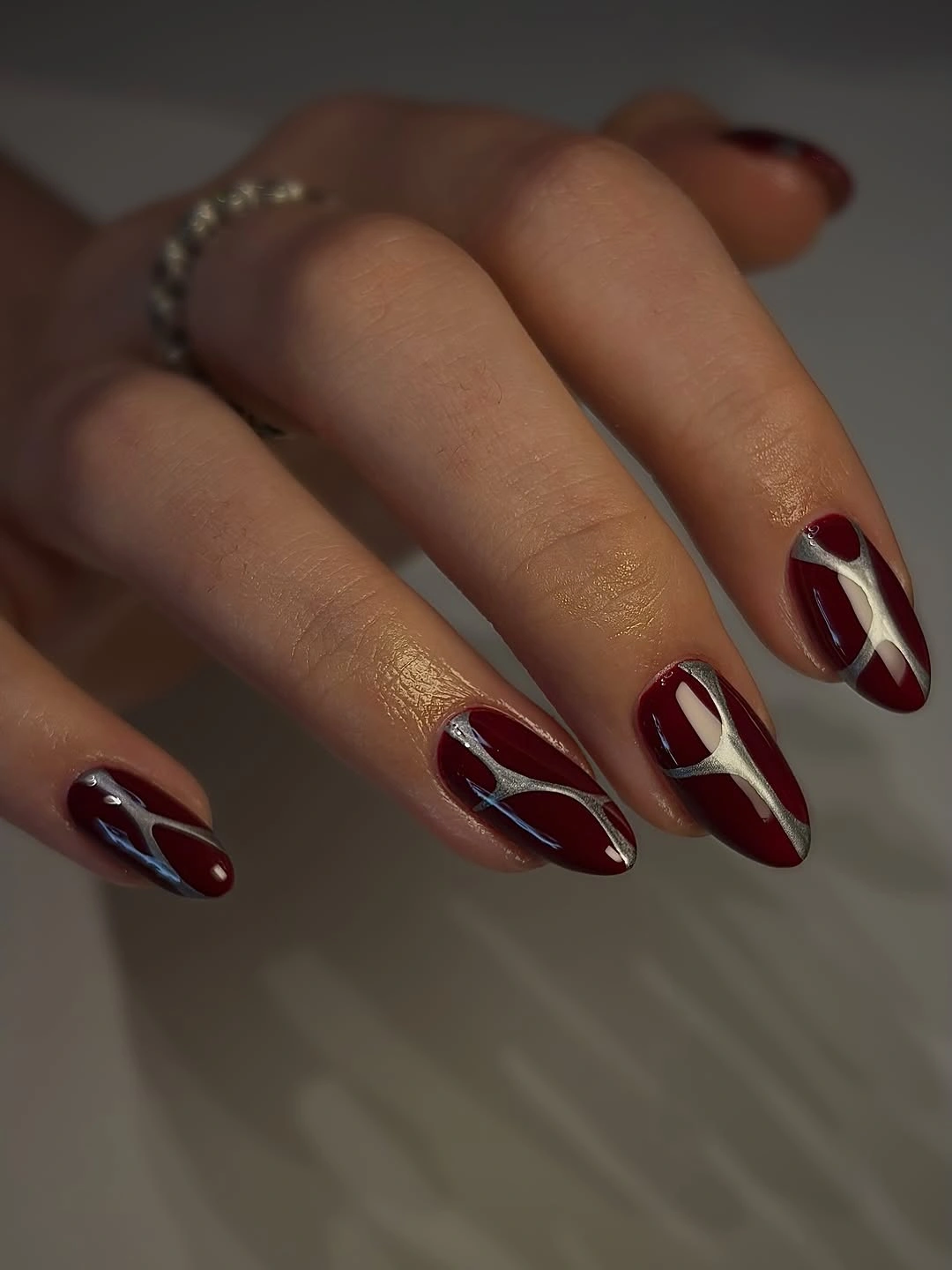 Burgundy almond nails with pale curved accent lines