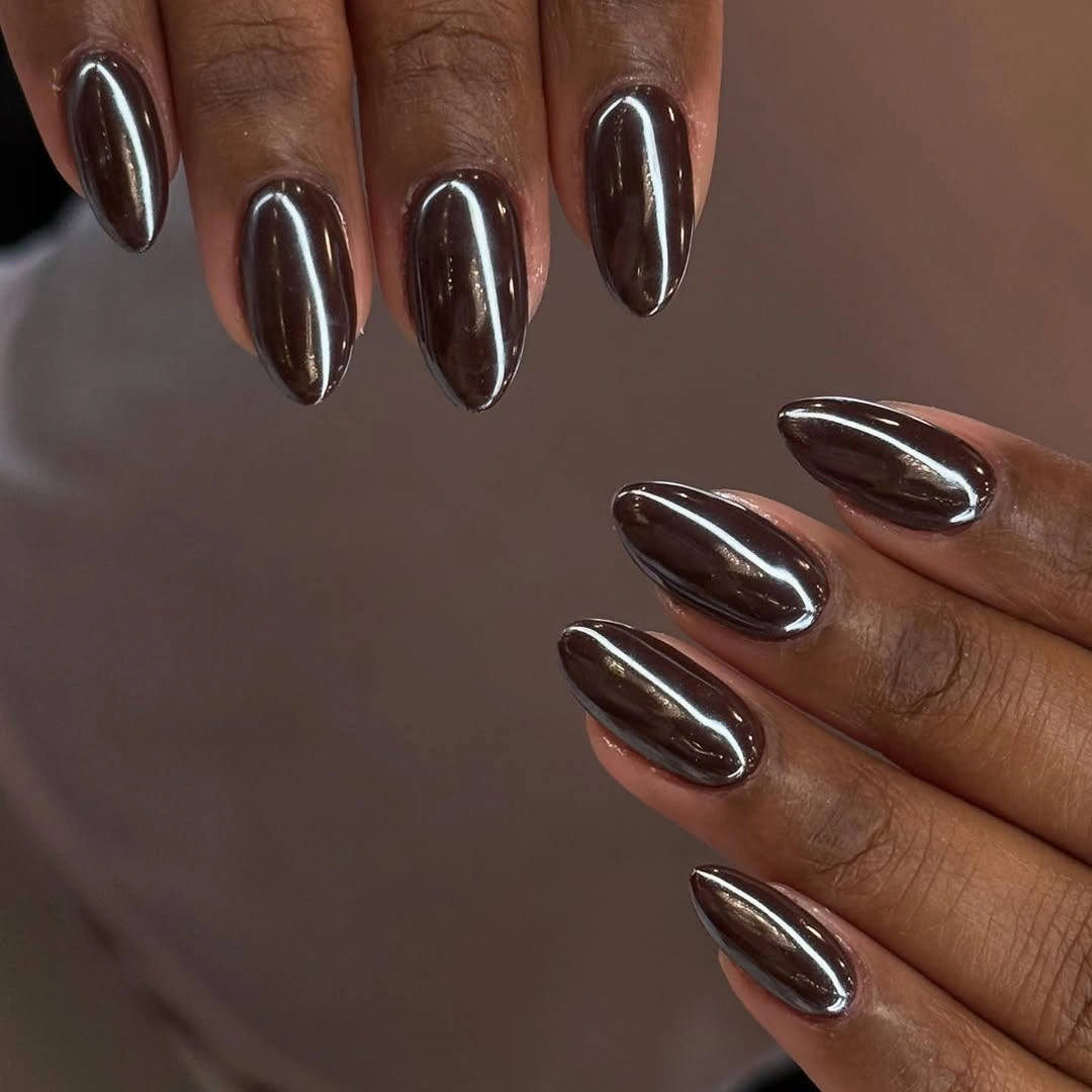 Reflective deep brown almond nails on a dark skin tone
