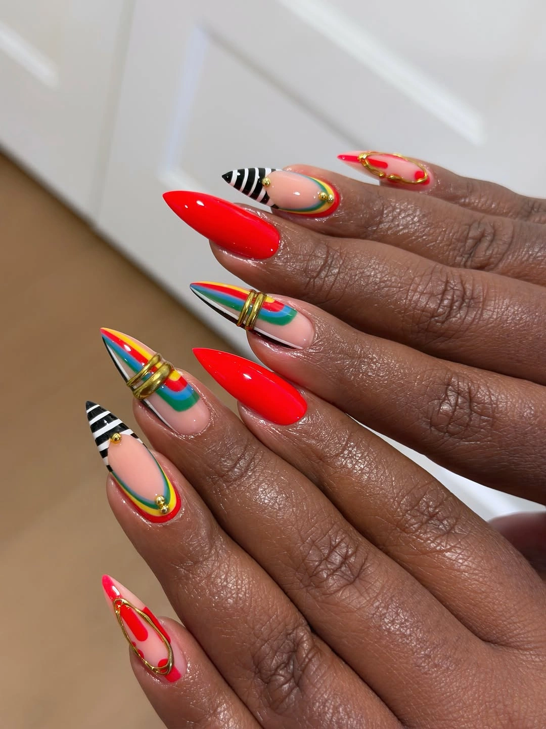 bright red nails with colorful curved accents
