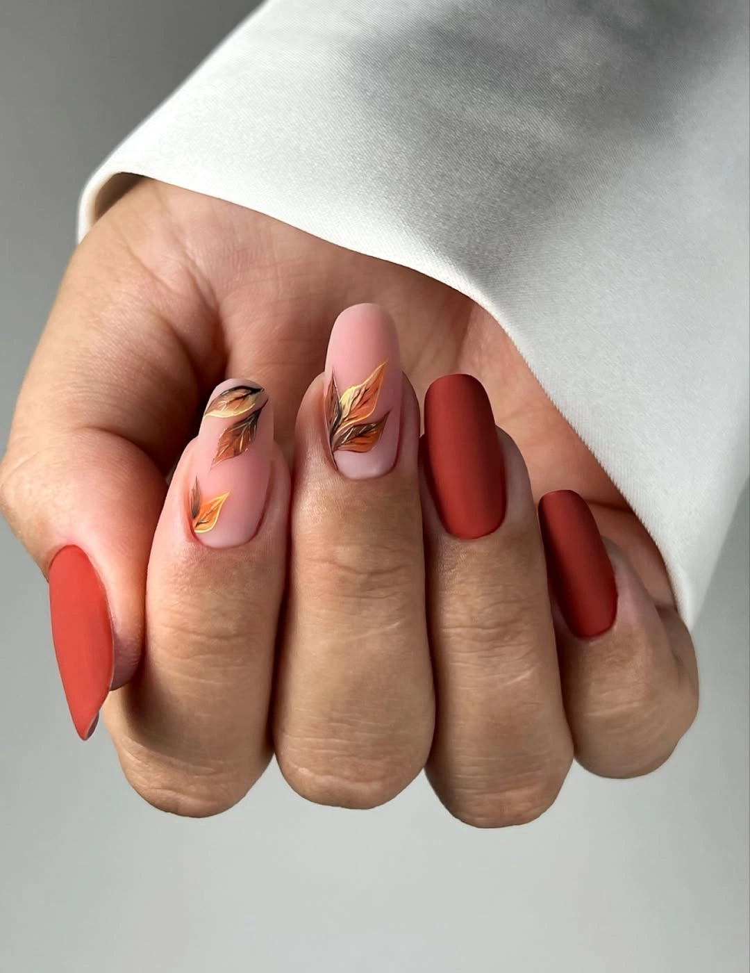 Red orange nails with pale gold-like accent marks