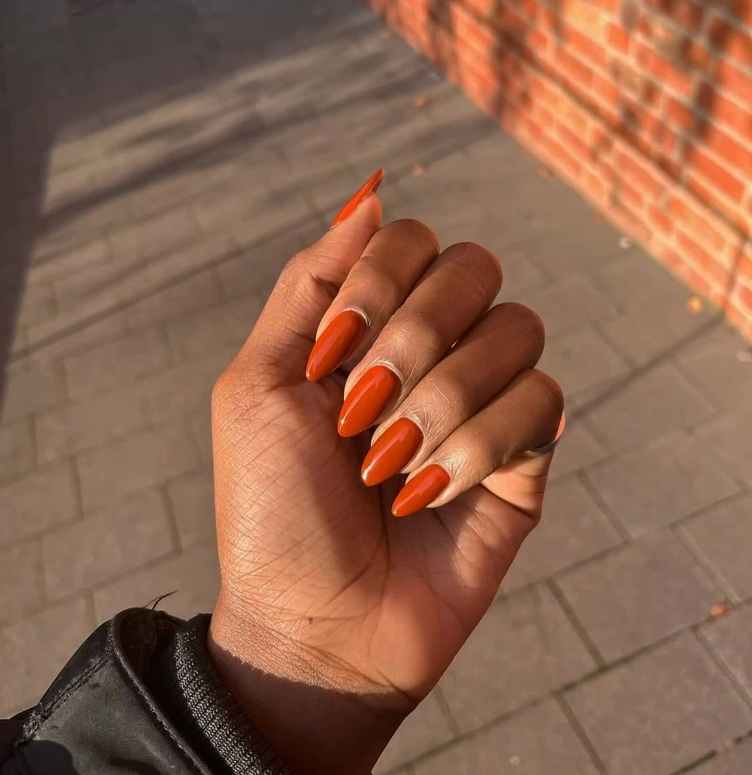 Vivid glossy orange on long almond nails