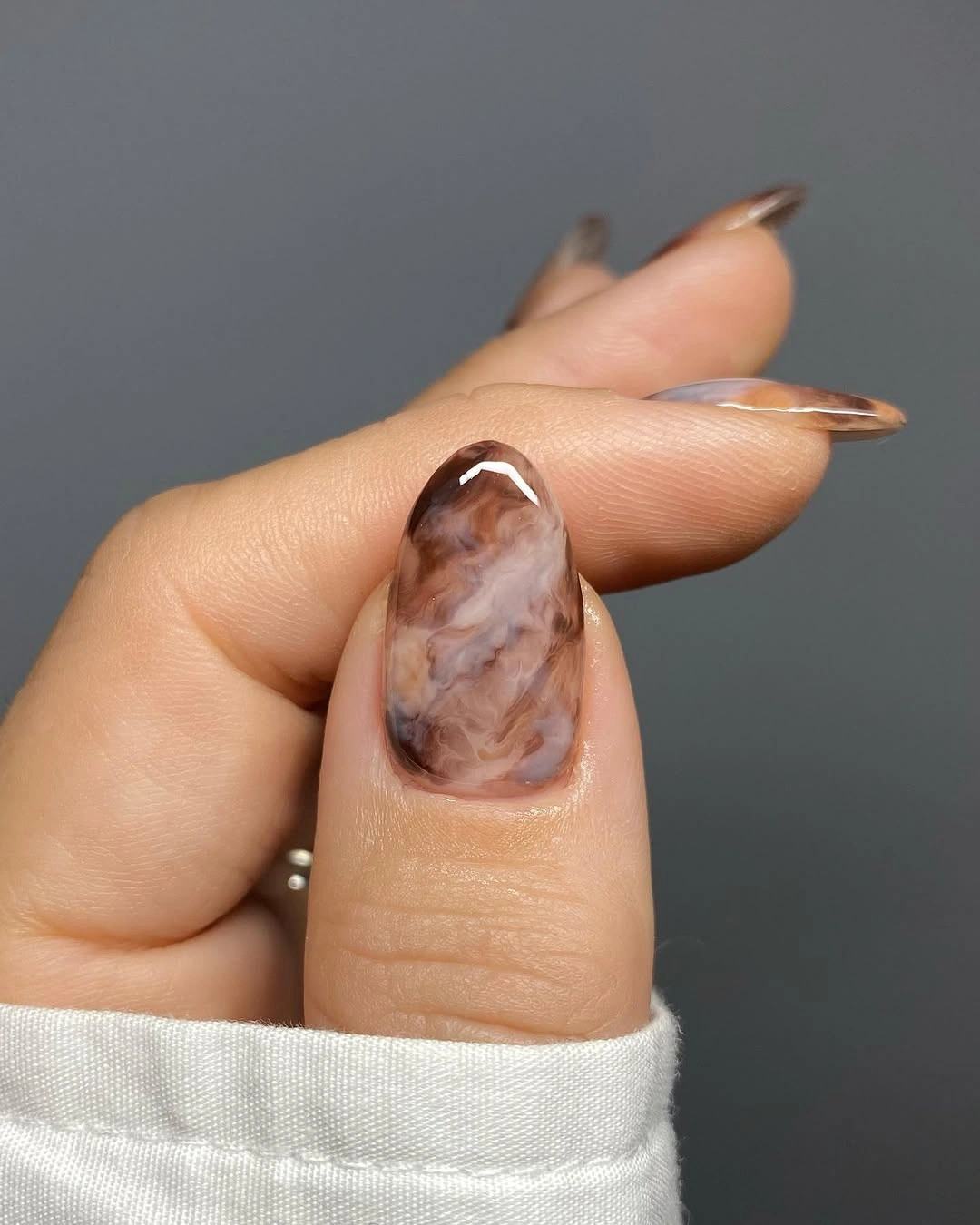 Translucent nude almond nails with one cloudy brown accent