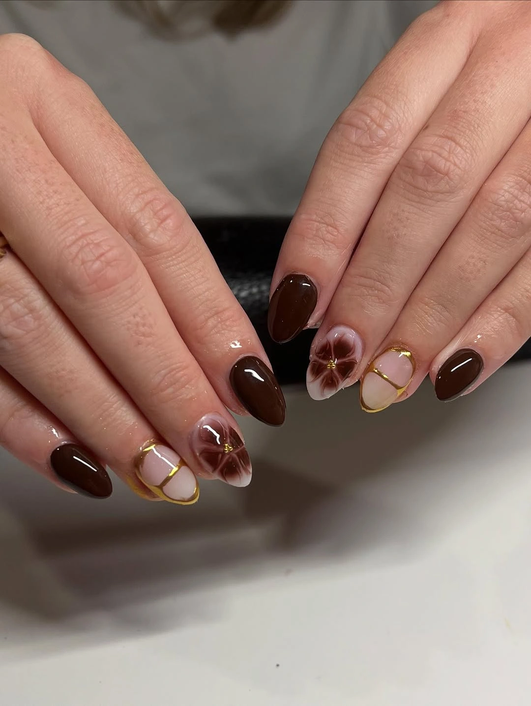 Brown almond nails with pale accents and fine warm outlines
