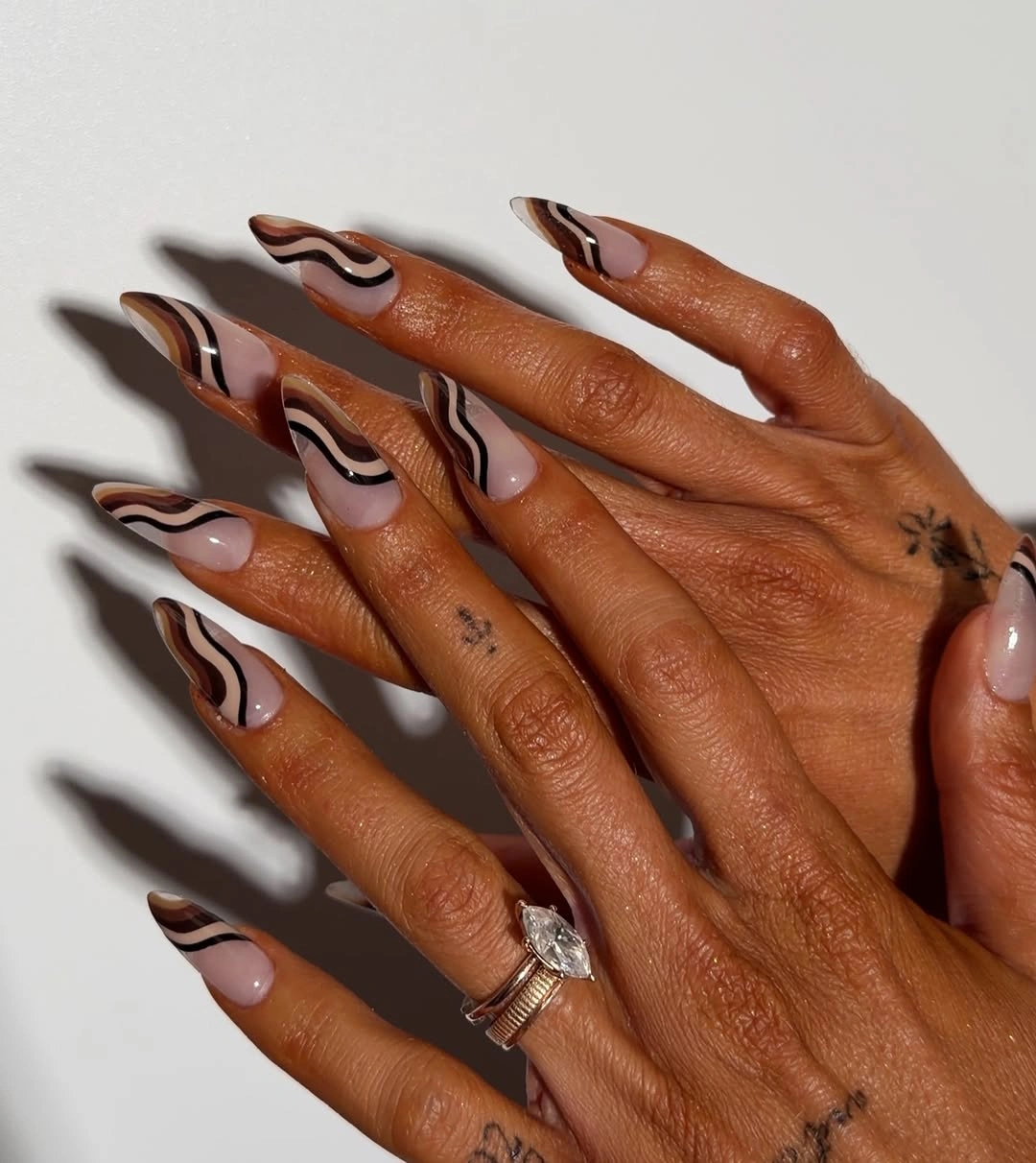 Pale almond nails with layered brown and cream waves