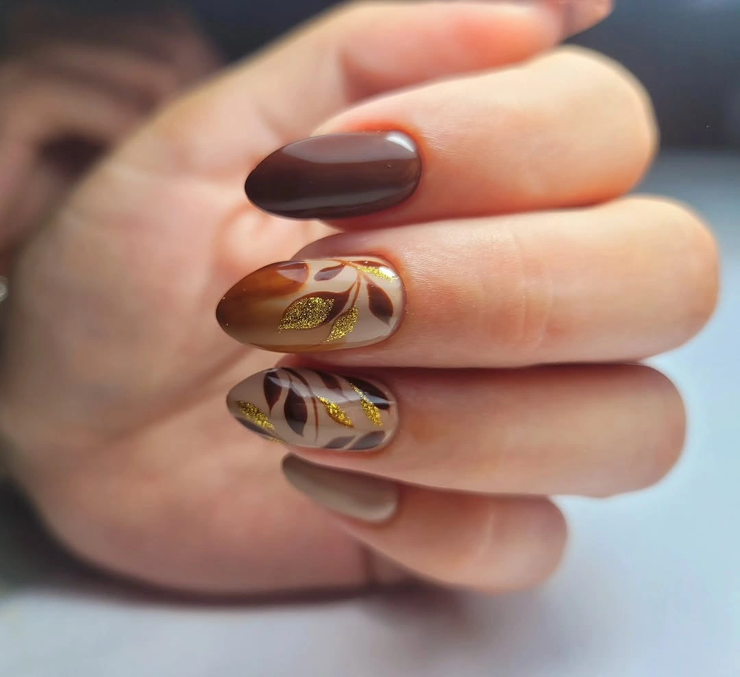 Pale almond nails with dark brown patterns and tiny accents
