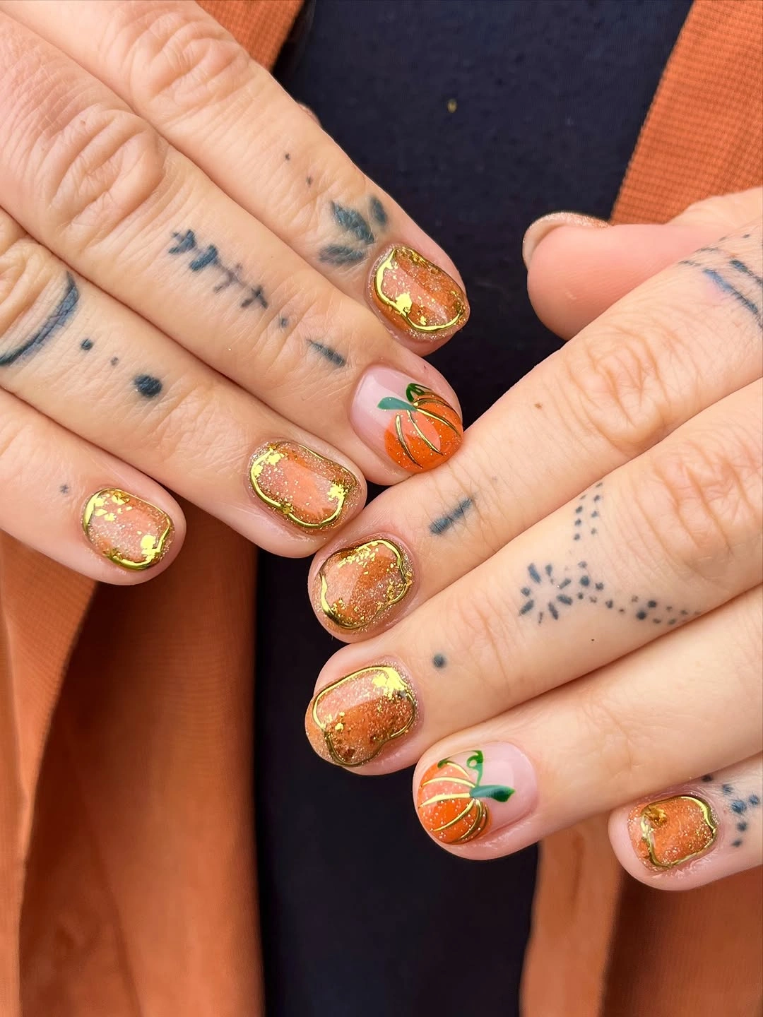 Short rounded gold nails with tiny orange pumpkins and leaves