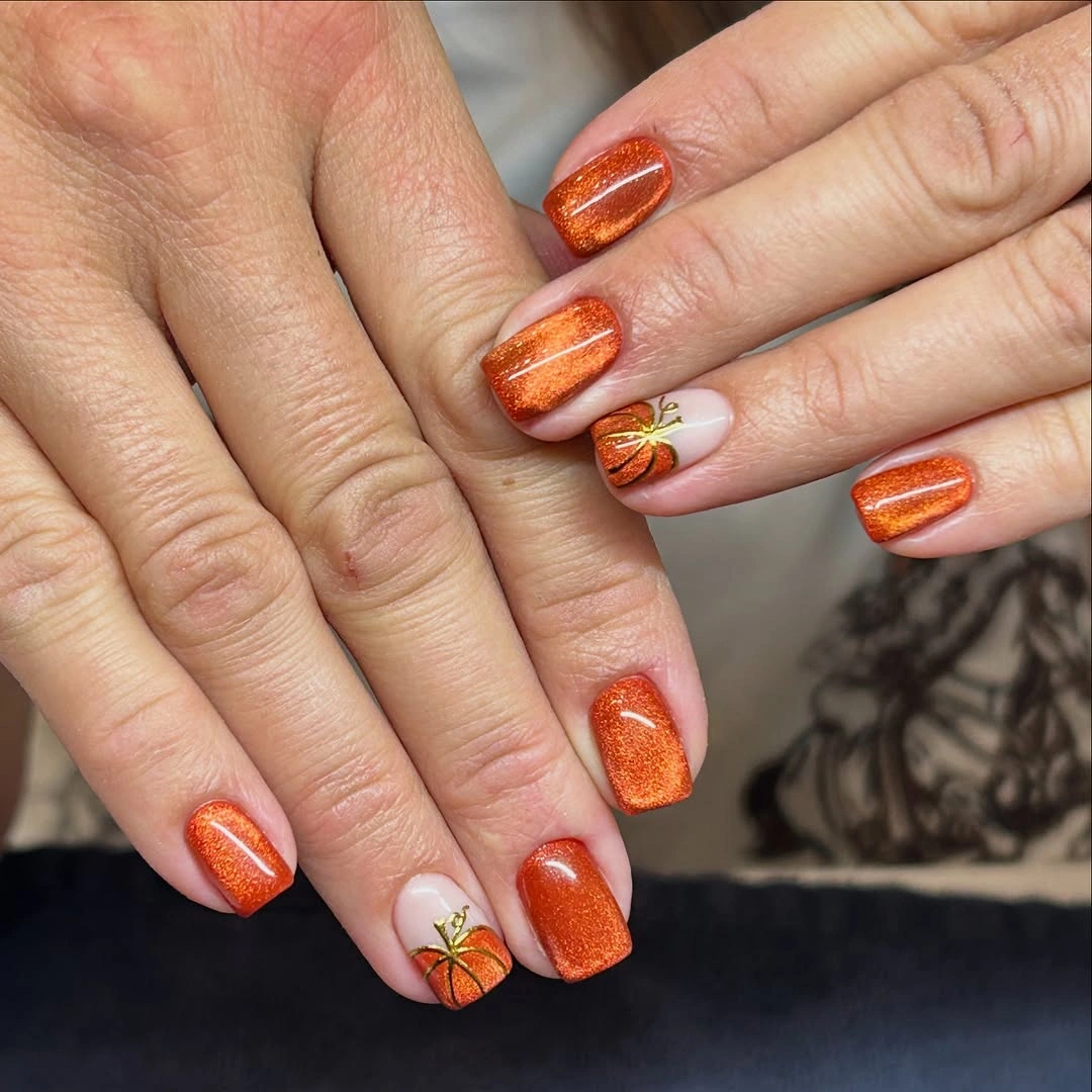 Short square orange shimmer nails with small pumpkins